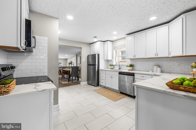 kitchen featuring sink, appliances with stainless steel finishes, light stone counters, white cabinets, and decorative backsplash