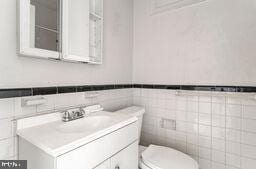 bathroom featuring vanity, tile walls, and toilet