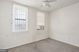 unfurnished room with ceiling fan and dark colored carpet