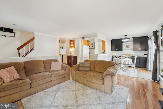 living room with crown molding, stairway, and light wood finished floors