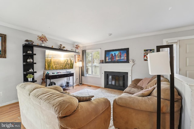 living area with light wood-style floors, a glass covered fireplace, crown molding, and baseboards