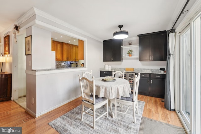 dining area with crown molding, light wood finished floors, and baseboards