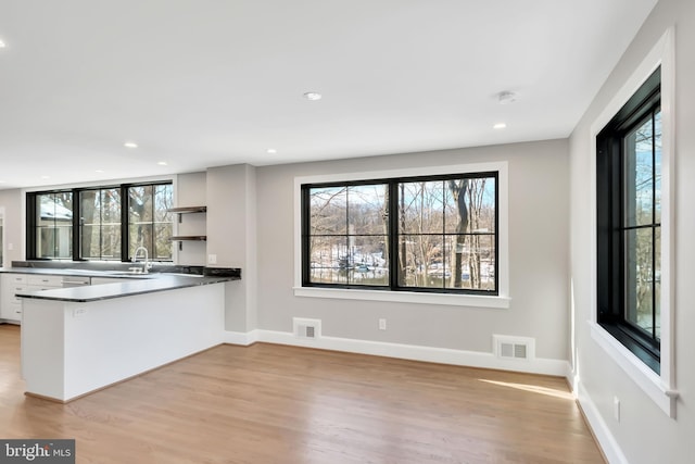 kitchen featuring sink, light hardwood / wood-style flooring, white cabinets, and kitchen peninsula