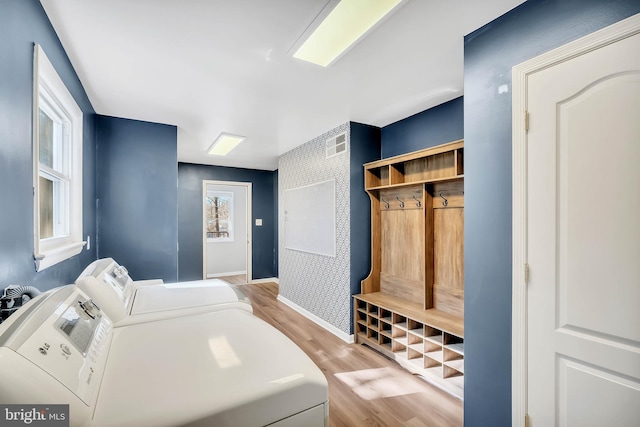 laundry room with separate washer and dryer and light hardwood / wood-style floors