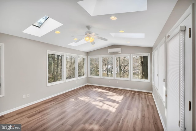 unfurnished sunroom featuring ceiling fan, a wall unit AC, and vaulted ceiling with skylight