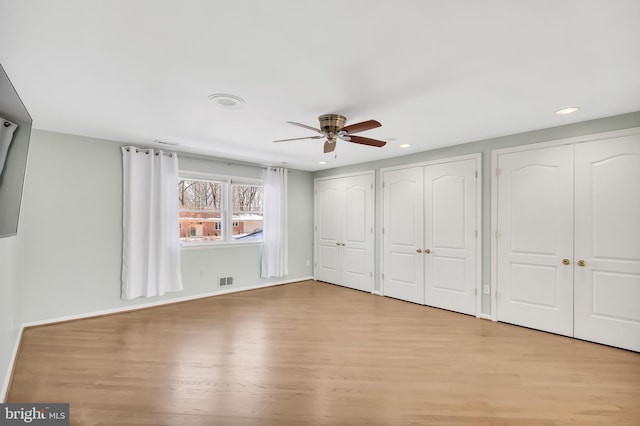 unfurnished bedroom with multiple closets, ceiling fan, and light hardwood / wood-style floors