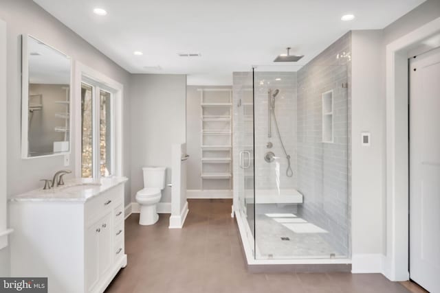 bathroom featuring vanity, toilet, and a shower with shower door