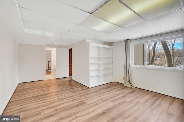 basement with a drop ceiling and light hardwood / wood-style floors