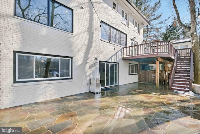 back of house with a wooden deck and a patio