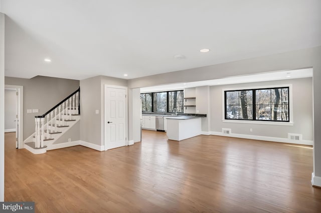 unfurnished living room featuring sink and light hardwood / wood-style flooring