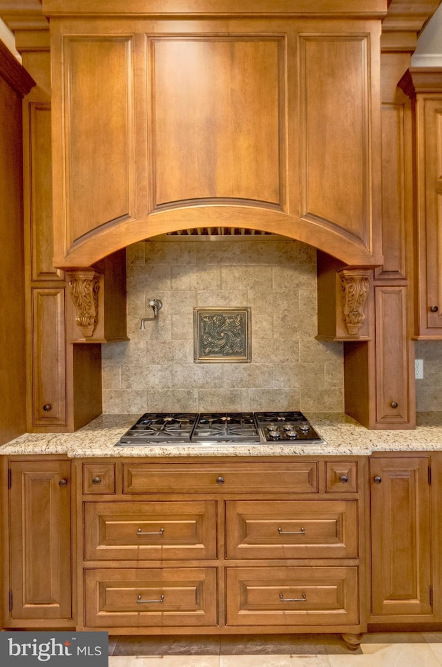 kitchen featuring stainless steel gas cooktop, backsplash, and light stone counters