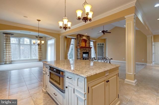 kitchen with pendant lighting, a center island, a fireplace, light stone countertops, and ornate columns