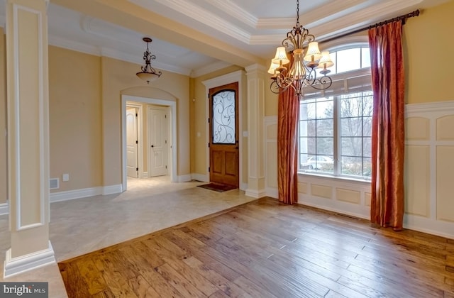 entryway with ornamental molding, a healthy amount of sunlight, a notable chandelier, and light hardwood / wood-style flooring