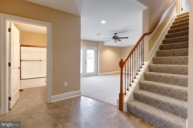 stairs with french doors, ceiling fan, and carpet