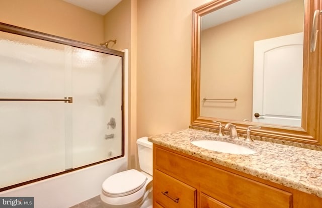 full bathroom with enclosed tub / shower combo, vanity, and toilet