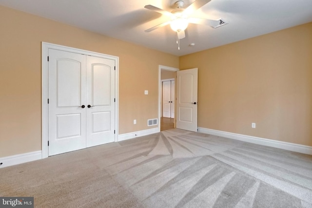 unfurnished bedroom featuring light carpet, a closet, and ceiling fan