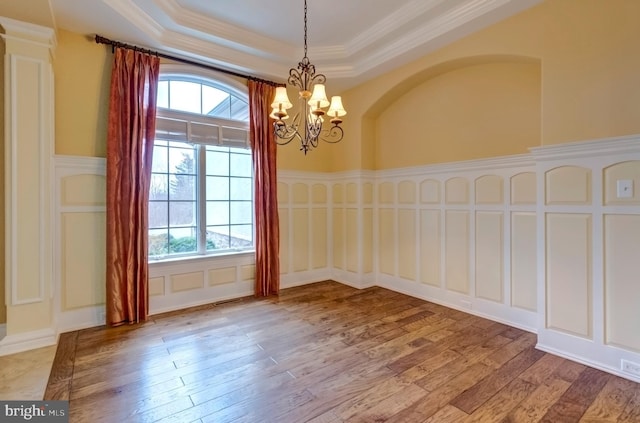 unfurnished room featuring ornamental molding, plenty of natural light, a tray ceiling, and light wood-type flooring