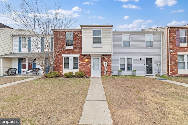 townhome / multi-family property featuring a front yard and brick siding