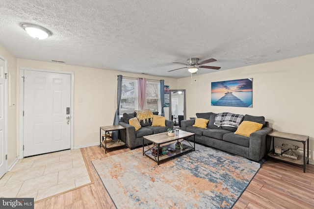 living room with light wood-style floors, ceiling fan, a textured ceiling, and baseboards