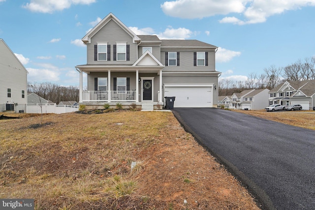 view of front of property with cooling unit, a garage, a front yard, and covered porch