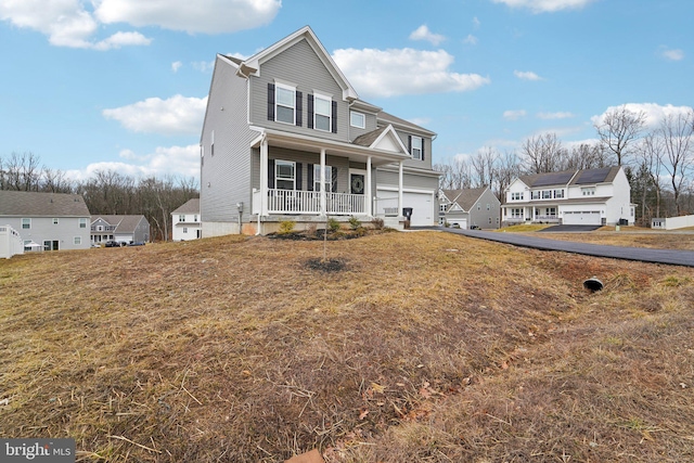 view of front of property featuring a garage, a front lawn, and a porch