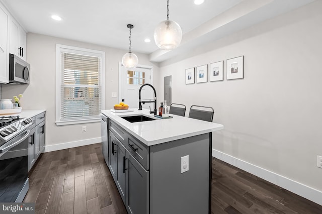 kitchen with gray cabinets, light countertops, appliances with stainless steel finishes, dark wood-type flooring, and a sink