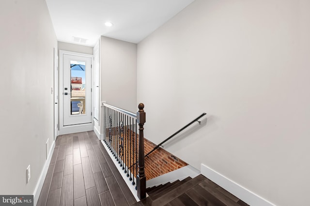 stairway featuring visible vents, baseboards, and wood finished floors