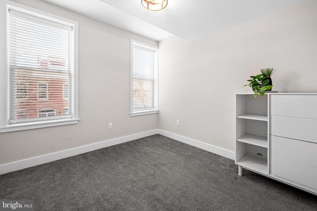 unfurnished bedroom featuring baseboards and dark carpet