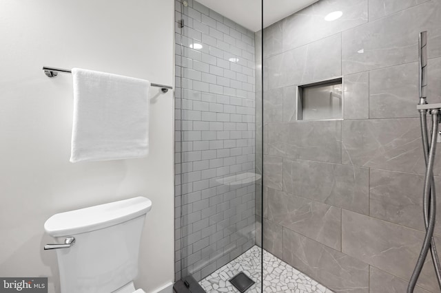 full bath featuring tiled shower and toilet