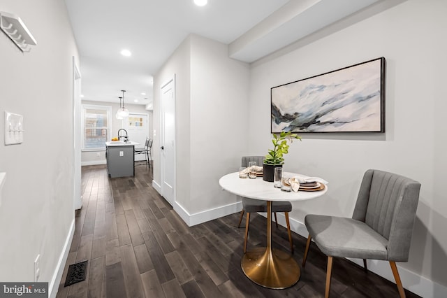 corridor featuring recessed lighting, dark wood-type flooring, a sink, visible vents, and baseboards