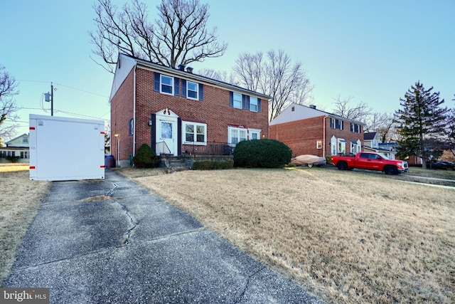 colonial home featuring brick siding and a front yard