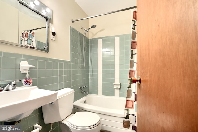 full bath featuring bathing tub / shower combination, toilet, tile walls, and a sink