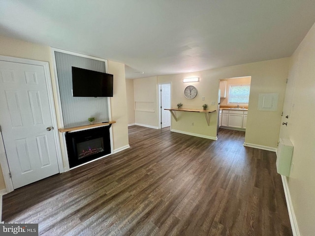 unfurnished living room with sink and dark wood-type flooring