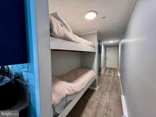 bedroom featuring ornamental molding, a textured ceiling, and light wood-type flooring