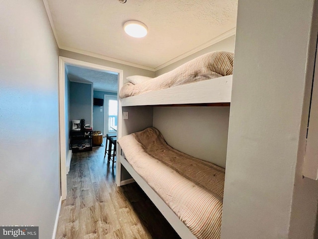 bedroom featuring light hardwood / wood-style flooring, ornamental molding, and a textured ceiling