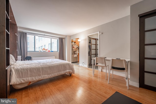 bedroom featuring freestanding refrigerator, baseboards, and wood finished floors