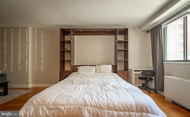 bedroom with radiator heating unit and wood finished floors