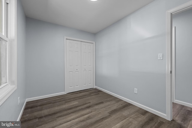 unfurnished bedroom with dark hardwood / wood-style flooring and a closet