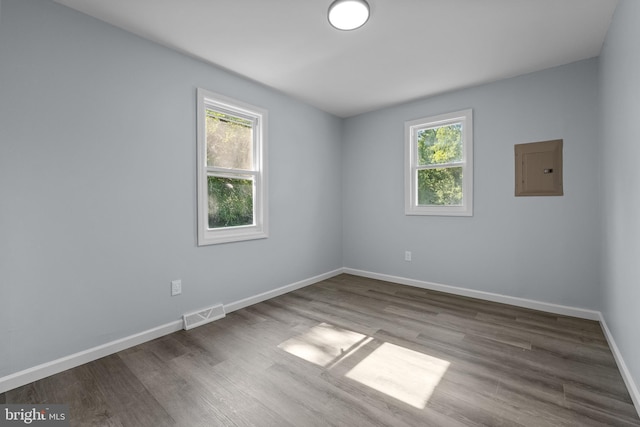 unfurnished room featuring electric panel and hardwood / wood-style floors