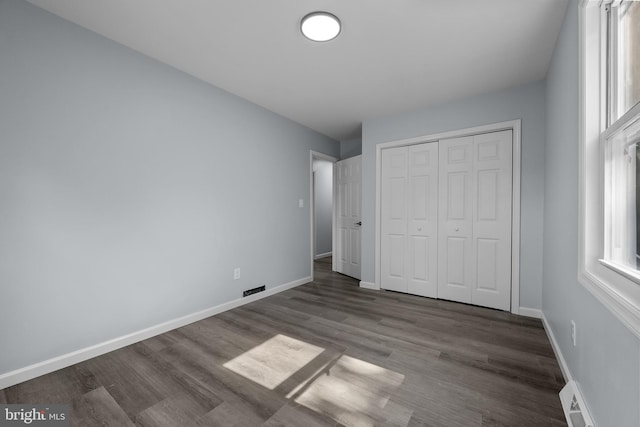 unfurnished bedroom featuring dark hardwood / wood-style floors and a closet