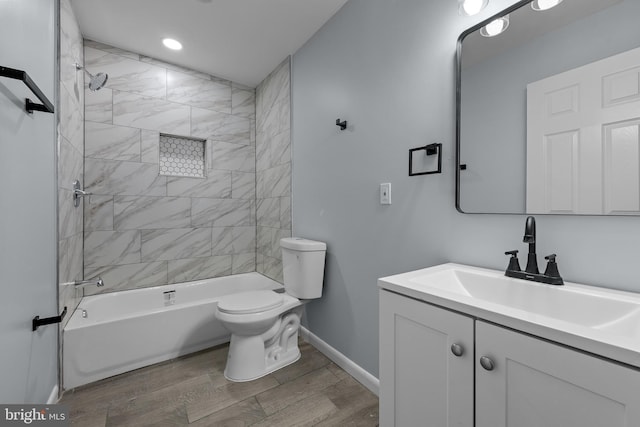 full bathroom with vanity, tiled shower / bath, hardwood / wood-style floors, and toilet