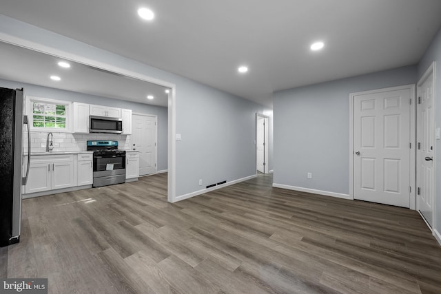 kitchen featuring appliances with stainless steel finishes, sink, white cabinets, decorative backsplash, and light hardwood / wood-style floors