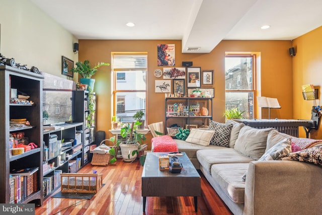 living room with wood-type flooring, visible vents, and recessed lighting