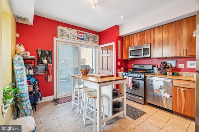 kitchen featuring visible vents, baseboards, appliances with stainless steel finishes, brown cabinets, and light tile patterned flooring