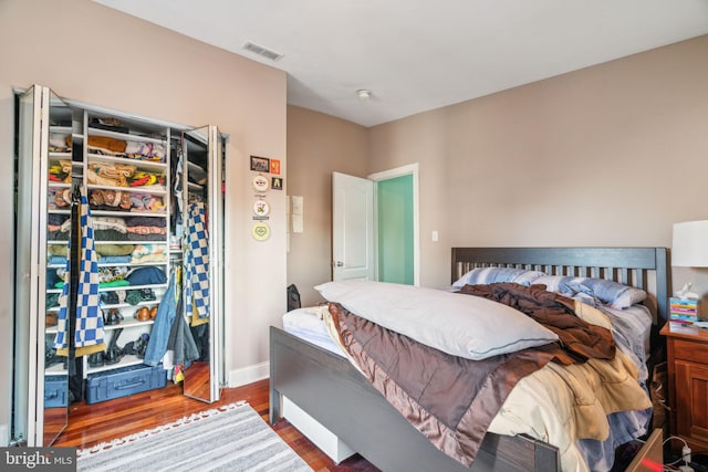 bedroom with visible vents, baseboards, and wood finished floors