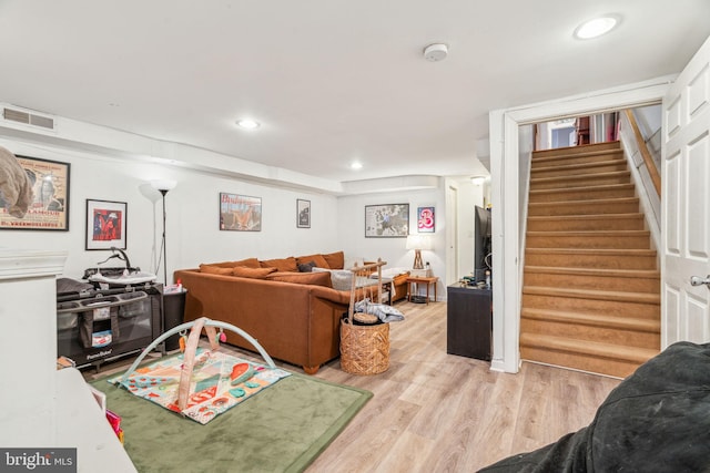 living room featuring recessed lighting, visible vents, light wood finished floors, and stairs