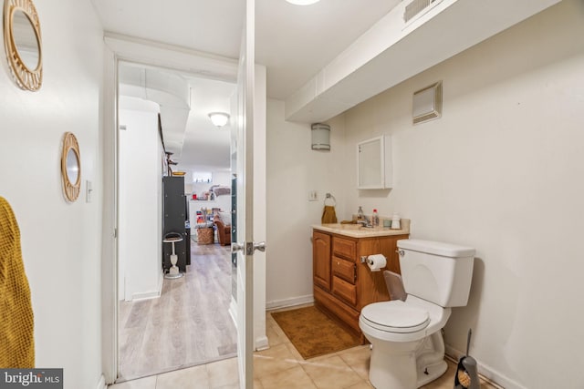 bathroom with visible vents, toilet, vanity, baseboards, and tile patterned floors