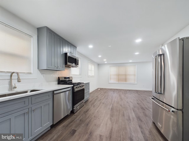 kitchen featuring sink, gray cabinets, stainless steel appliances, tasteful backsplash, and dark hardwood / wood-style flooring