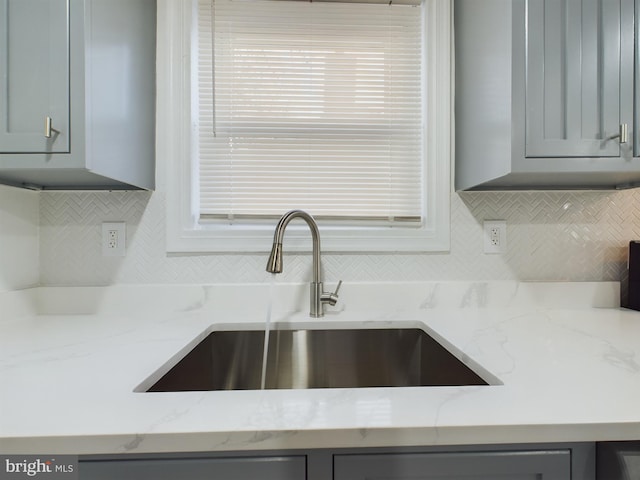 details featuring light stone counters, sink, and gray cabinetry