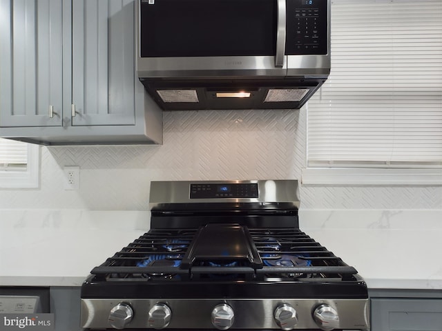 kitchen with stainless steel appliances, gray cabinets, and backsplash